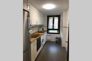 eine Küche mit weißen Schränken, einer Spüle und einem Geschirrspüler in der Unterkunft Rincon de Pepo in Villanúa