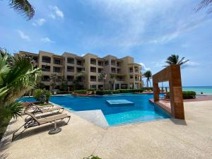 a resort swimming pool with two chairs and a building at El Faro 304 Coral Penthouse in Playa del Carmen