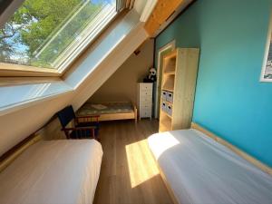 een zolderslaapkamer met twee bedden en een raam bij Het Achterhoeks Voorrecht in Aalten