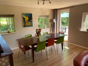 een eetkamer met een houten tafel en groene stoelen bij Het Achterhoeks Voorrecht in Aalten