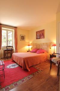 a bedroom with a bed and a red rug at L’Auberge du Sombral in Saint-Cirq-Lapopie