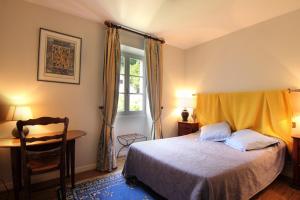 a bedroom with a bed and a desk and a window at L’Auberge du Sombral in Saint-Cirq-Lapopie