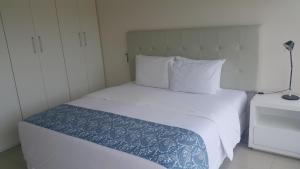 1 dormitorio con cama blanca y edredón azul en START Villa Morra Rent Apartments en Asunción