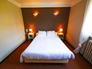 a bedroom with a large white bed with two lamps at Auberge de la Tour in Aups
