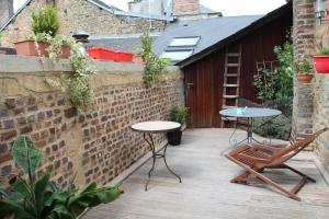 a patio with two tables and chairs on a brick wall at Côté Chambres in Charleville-Mézières