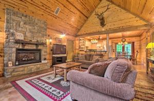 a living room with a stone fireplace in a log cabin at Spacious Family Home with Fire Pit by Norfork Lake! in Mountain Home
