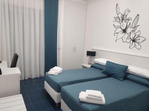 twee bedden in een kamer met blauw en wit bij Hotel Villa Chiara in Terracina