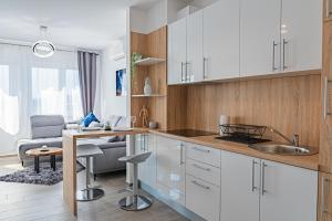 cocina con armarios blancos y sala de estar. en Jacuzzi - Flexible SelfCheckIns 20 - Zagreb - Luxury - Garage - Smart - Brand New - Apartments Repinc, en Zagreb