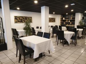 een eetkamer met witte tafels en zwarte stoelen bij Le Patio De La Dordogne in Souillac