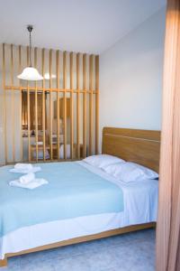 Schlafzimmer mit einem Bett mit einem Kopfteil aus Holz in der Unterkunft Vasilis Apartments in Ermioni