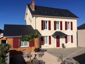 une grande maison blanche avec des volets rouges et des chaises dans l'établissement Chez Juliette Maison Gite Hôtel, à Rontignon