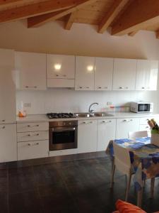 een keuken met witte kasten, een tafel en een wastafel bij Residence Antares in Caorle
