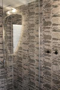 a bathroom with a glass shower with a stone wall at Cycladic Villa in Amorgos Island (Maison Shiro) in Arkesíni