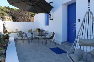 a patio with a table and chairs and an umbrella at Cycladic Villa in Amorgos Island (Maison Shiro) in Arkesíni