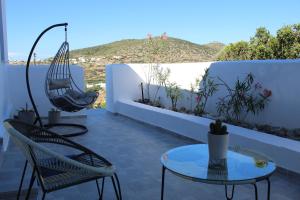 a patio with chairs and tables and a hammock at Cycladic Villa in Amorgos Island (Maison Shiro) in Arkesíni