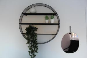 a black rattan shelf with plants and a mirror at Cycladic Villa in Amorgos Island (Maison Shiro) in Arkesíni