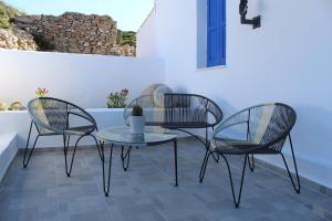 three chairs and a table on a patio at Cycladic Villa in Amorgos Island (Maison Shiro) in Arkesíni