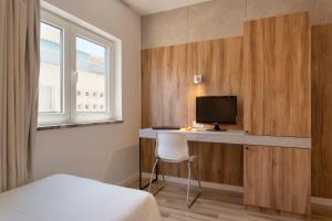 1 dormitorio con 1 cama y escritorio con TV en Hotel Made Inn en Portimão
