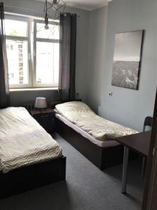 two beds in a room with two windows at SHIRE Gdynia in Gdynia
