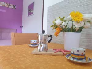 Eine Kaffeekanne und Tassen auf einem Tisch mit Blumen in der Unterkunft Monolocale Viola - A casa di Ludovica e Martina in Gallipoli + 1 Foto