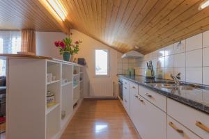a large kitchen with white cabinets and a wooden ceiling at Swiss Mountains Apartments in Interlaken