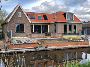 a house under construction next to a body of water at B&B De Gulden Halsband Pingjum in Pingjum +16 photos