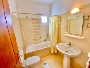 a bathroom with a sink and a toilet and a tub at Zoom Beach Hotel in Kandia