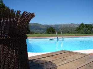 a blue swimming pool with a wooden table next to it at Casa d'Aldeia de Souto de Lafões OLIVEIRA DE FRADES in Oliveira de Frades