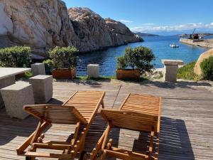 two wooden chairs sitting on a wooden deck with a view of the water at La Maddalena Exclusive villas in La Maddalena