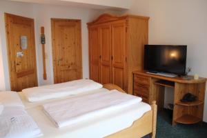 a bedroom with two beds and a desk with a television at Gasthof Diewald in Raach am Hochgebirge