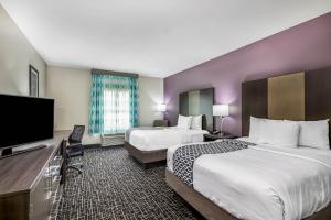 a hotel room with two beds and a flat screen tv at La Quinta by Wyndham Claremore in Claremore