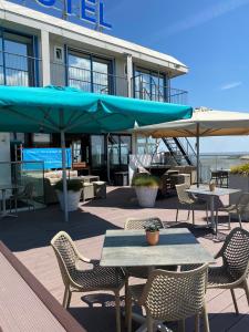 eine Terrasse mit Tischen, Stühlen und Sonnenschirmen in der Unterkunft Eemshotel in Delfzijl