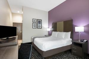 a hotel room with a bed and a flat screen tv at La Quinta by Wyndham Claremore in Claremore