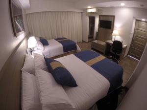 a hotel room with two beds and a desk at Hotel Mansur Business & Leisure in Córdoba