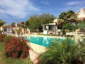 a swimming pool in front of a house at Spacious apartment in Pozzallo, sea view, shared pool in Pozzallo