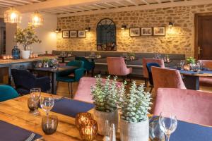a table in a restaurant with chairs and tables and wine glasses at Hôtel restaurant l'Epicurien in Valognes