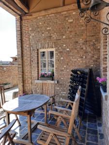 a patio with a table and chairs and a brick wall at Het Stalhuys in Riemst