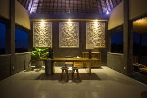 a dining room with a table and two stools at Manyi Village Ubud in Ubud