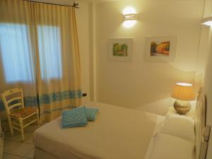 a bedroom with a bed and a chair and a window at Hotel Mariposas in Villasimius