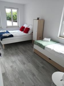 zwei Betten in einem Zimmer mit Holzboden und Fenstern in der Unterkunft Armona in Ustka
