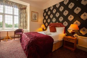 a hotel room with a bed and a desk and a window at Westone Manor Hotel in Northampton