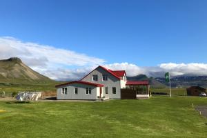 a house in a field with a mountain in the background at Sudur-Bár Guesthouse in Grundarfjordur