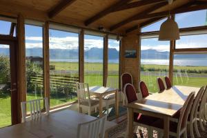 uma sala de jantar com mesas e cadeiras e uma grande janela em Sudur-Bár Guesthouse em Grundarfjordur