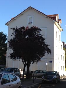 un bâtiment blanc avec des voitures garées devant lui dans l'établissement Confort douceur et calme dans Grenoble, à Grenoble