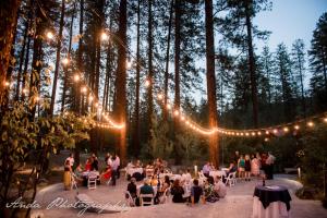 um grupo de pessoas sentadas em mesas em um jardim com luzes em Sleeping Lady Mountain Resort em Leavenworth