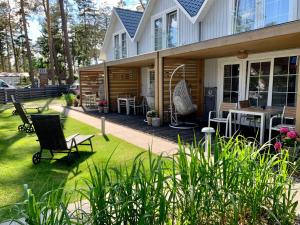 una casa con un patio con sillas y una mesa en Baltic Sky, en Pobierowo