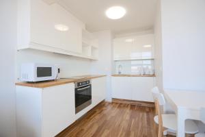 cocina con armarios blancos, mesa y microondas en Lys Apartments City Center, en Pärnu