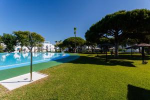 a swimming pool in a park with trees and grass at La Almadraba in Chiclana de la Frontera