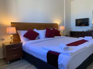 a bedroom with a large white bed with red pillows at Petra Sky Hotel in Wadi Musa