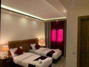 two beds in a hotel room with red curtains at Petra Sky Hotel in Wadi Musa